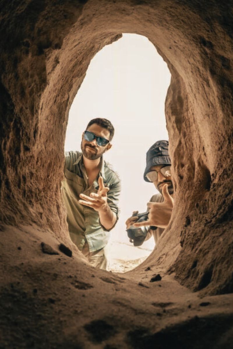 two guys exploring a rock opening
